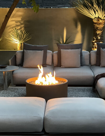 Outdoor lounge area with a fire pit and comfortable seating at dusk.