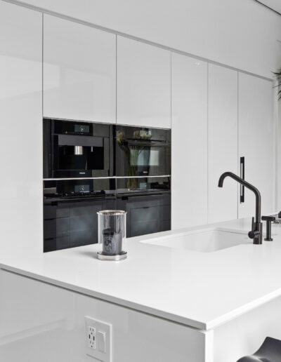 Modern kitchen with white cabinetry, a central island, and black appliances.