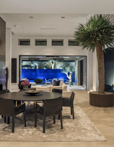 Modern dining room with a round table, leading to a patio with pool view.