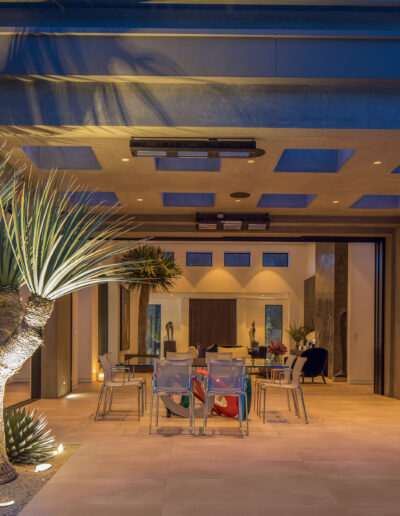 Modern living room with open-plan design, featuring elegant lighting, a dining area, and desert-inspired landscaping indoors.