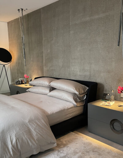 A modern bedroom with a neatly made bed, matching nightstands, and minimalist decor.