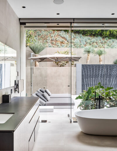 Modern bathroom with a freestanding tub, walk-in shower, and large window with a garden view.